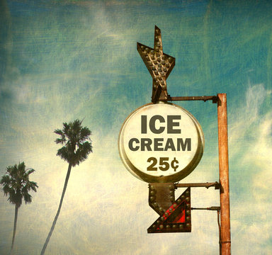 aged and worn vintage photo of retro ice cream sign with palm trees