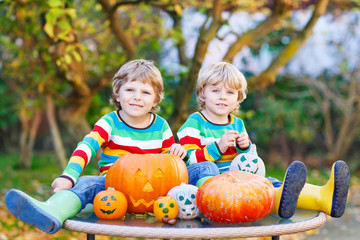 Two little friends boys making jack-o-lantern for halloween in a