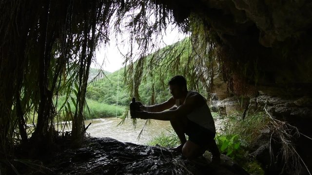 Hiker collecting water dripping from cave