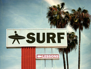 aged and worn vintage photo of surf lessons sign on beach