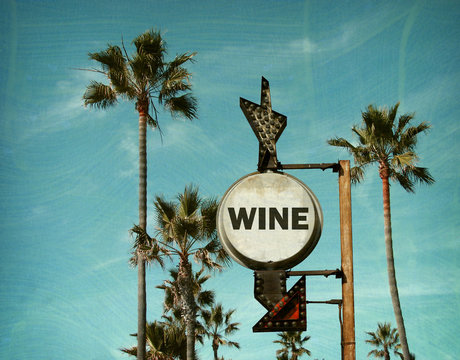 aged and worn vintage photo of wine sign on beach with palm trees
