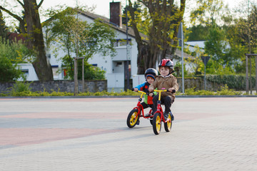 Two little siblings having fun on bikes in city on vacations