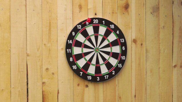 Someone throws a dart misses dart board
