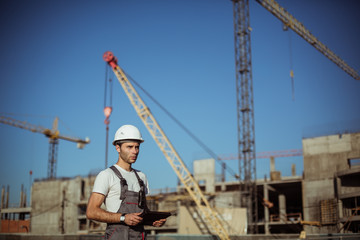 Engineer builder using tablet and walkie talkie, giving instructions at a construction site