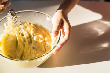 Hands of boy mixing muffin dough in transparent glass bowl