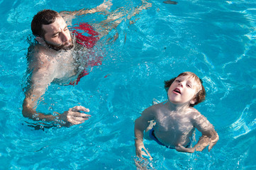 Niño aprendiendo a nadar con su padre