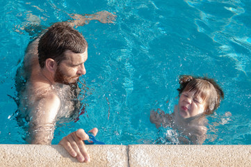 Niño aprendiendo a nadar con su padre