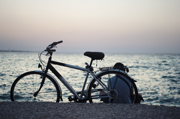 Suggestiva immagine di un ragazzo che ascolta musica al tramonto seduto dietro la sua bicicletta.