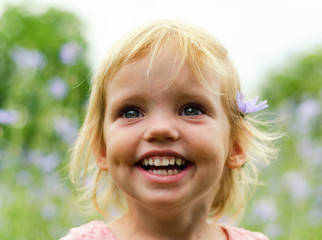 Cute little girl in a pink dress smiling in park