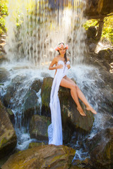 Fototapeta na wymiar Naked girl in a wreath at the waterfall.