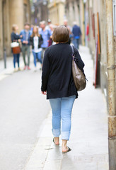 A woman is walking in the streets. Image taken in an European city.