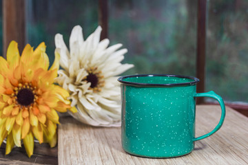 Retro green coffee mug with flowers and window in background