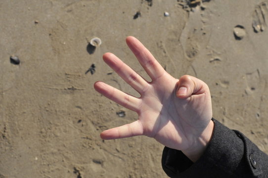 hand counting four on the beach