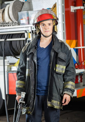 Confident Firefighter Holding Hose At Fire Station