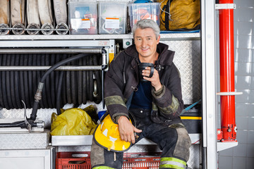 Fototapeta premium Smiling Fireman Sitting In Truck At Fire Station