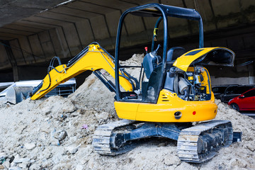 Mini yellow excavator on a construction site