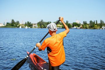 Fototapeta premium The boy rowing in a canoe on the river