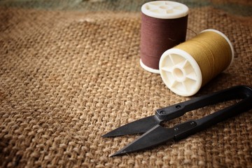 Sewing threads with scissors on sackcloth