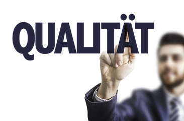 Businessman pointing the text: Quality (in German)