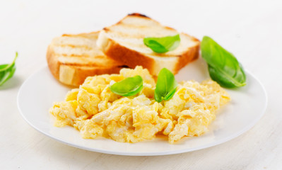 Scrambled eggs and toasts with basil.