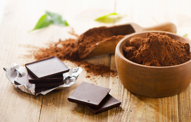 Chocolate bars and  wooden bowl of cacao powder.