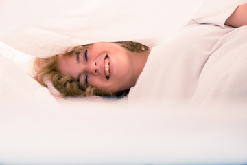 Young woman hiding in Bed under the sheets