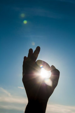 Sun in the hand on blue sky. Freedom, harmony, spirituality concept.
