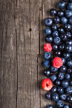 Forest blueberries and raspberries on an old wooden board