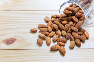 Almonds in the glass and pour on the wood, selective focus point
