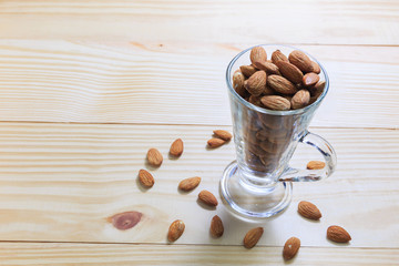 Almonds in the glass and place on the wood, selective focus point