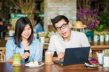 Couple business talking with laptop computer and drinking in caf