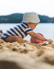 Cute baby boy playing with beach toys