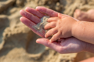 Mother and child's hands on the beach