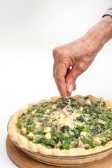 Agregando queso parmesano a un Quiche lorraine de espinaca y atún