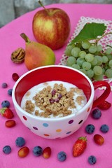Healthy breakfast: yogurt with muesli and fresh fruit in bowl on pink background