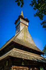 Fototapeta na wymiar Old wooden church in Budesti Josani village, Maramures county, northern Romania. Traditional wooden church in Maramures area, Romania