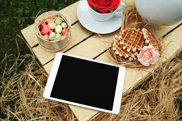 Top view digital tablet lying on wooden box with cookies, flower