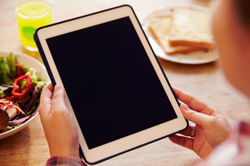 Person Looking At Digital Tablet Whilst Eating Lunch