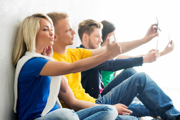 Fototapeta premium Group of happy students being on a break taking selfie. Focus on a grimacing girl. Background is blurry.