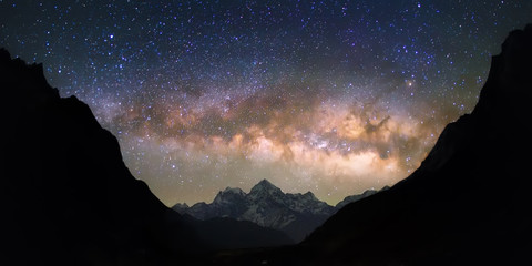 Schaal der Hemelen. Helder en levendig Melkwegstelsel over de besneeuwde bergen. Mooie sterrenhemel lijkt in een "kom" tussen de gesilhouetteerde heuvels te zijn.