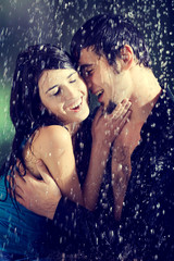 Young couple hugging and under a rain, in passion