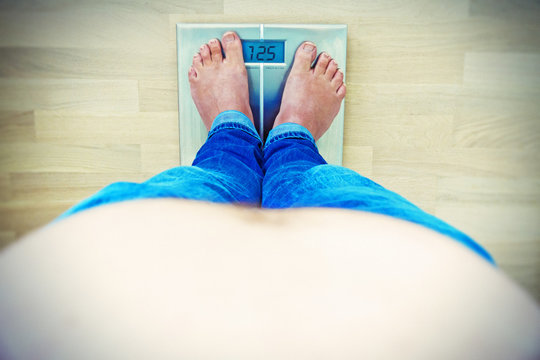 &Uuml;bergewicht - Mann mit Bauch auf einer Waage
