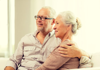 happy senior couple sitting on sofa at home