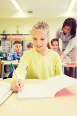 group of school kids writing test in classroom