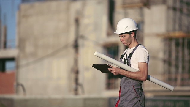 Engineer builder using tablet and walkie talkie, giving instructions at a construction site