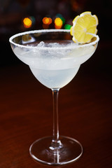 bright refreshing cocktail daiquiri on a table in a restaurant with creative decoration of orange slices and ice on a wooden table in a bar with a beautiful dance disco lights bokeh in the background.