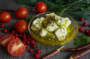 feta cheese in olive oil and herbs on a wooden table surrounded