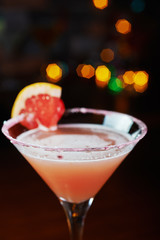 bright cocktails on a table in a restaurant with creative decoration of red orange slices on a wooden table in a bar with a beautiful dance disco lights bokeh in the background.
