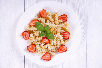 Pasta with strawberries on a plate. Top view.