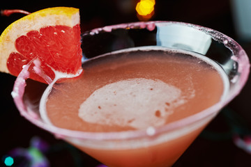 bright cocktails on a table in a restaurant with creative decoration of red orange slices on a wooden table in a bar with a beautiful dance disco lights bokeh in the background.